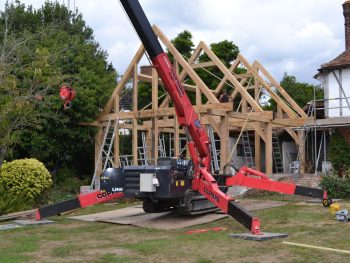 The oak frame being erected on site besides another house.