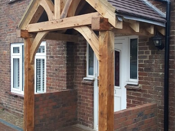 An open oak framed porch with a white door and partition wall