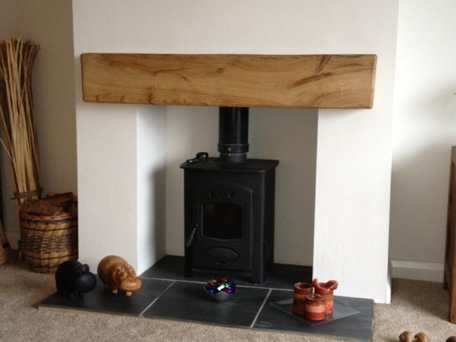 A fireplace with an oak beam mantel in the top.