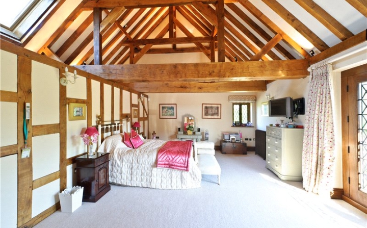 Large bedroom with oak frames beams with a bed in the middle.