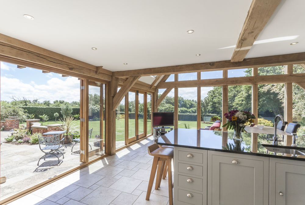 French oak doors in open white kitchen with ceiling beams.