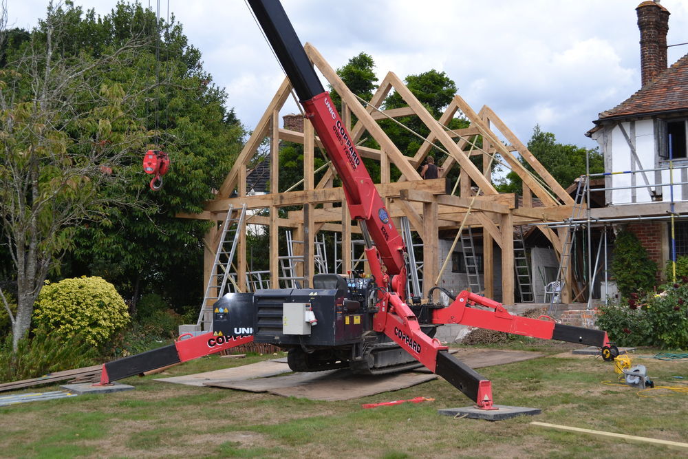 The oak frame being erected on site besides another house.