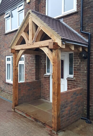 An open oak framed porch with a white door and partition wall