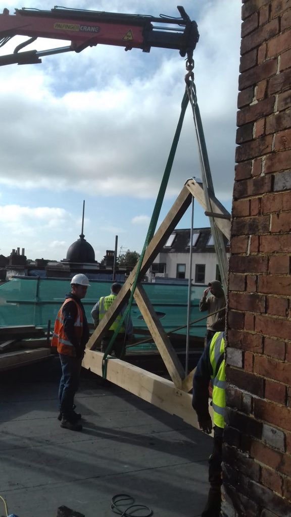 Oak trusses at an ongoing construction being lifted.