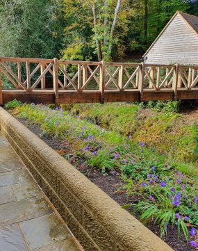 A wooden bridge made from oak beams over a river in the countryside.