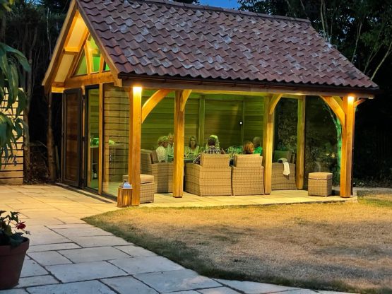 At night a lighted shed at the end of the garden with a outside seating area.