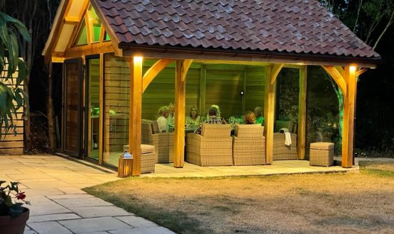 At night a lighted shed at the end of the garden with a outside seating area.