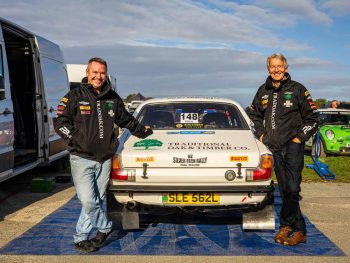Two rally car team members posing at back of car