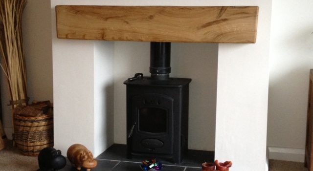 A fireplace with an oak beam mantel in the top