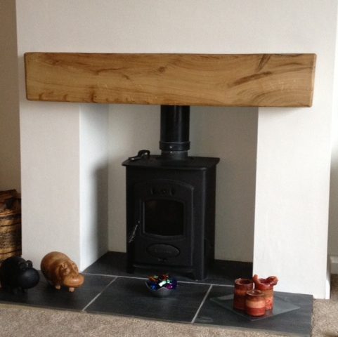 A fireplace with an oak beam mantel in the top