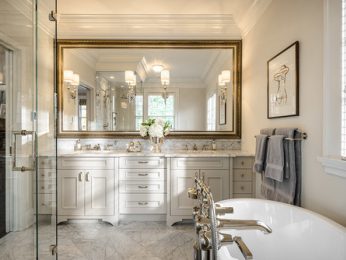 A wide white bathroom with a bathtub, a shower and two large sinks with a big mirror.